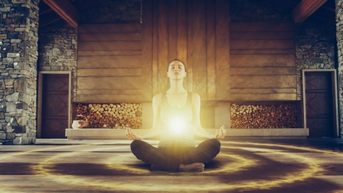 Woman sitting in yoga pose with bright light around her