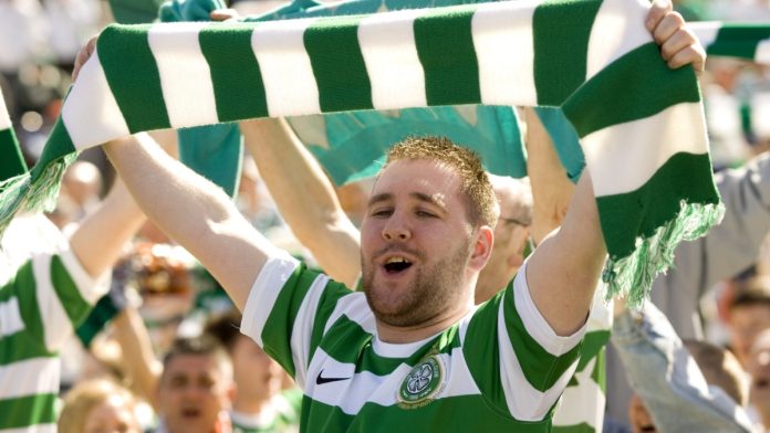 Celtic fan holding a green and white scarf over his head