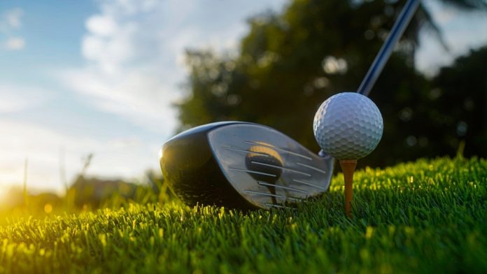 Driver face at back of golf ball on tee